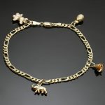 This ankle bracelet is crafted in 14k yellow gold and features 4 charms -  an elephant