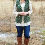 Army green vest, beige chiffon button down, skinny jeans, brown riding boots