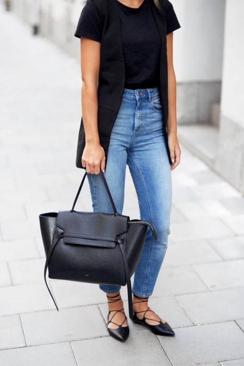 black tee tucked into jeans, a black vest and lace up flats work outfit